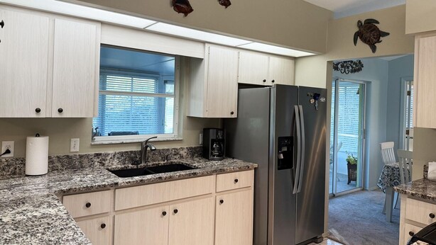 A kitchen with light wood cabinets, a stainless steel refrigerator, a granite countertop, and a window with blinds. - Peaceful 3BR Villa – Near Beaches & Golf (Englewood)