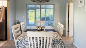 A dining area with a table set for four, a chandelier, and a view through a glass door. - Peaceful 3BR Villa – Near Beaches & Golf (Englewood)
