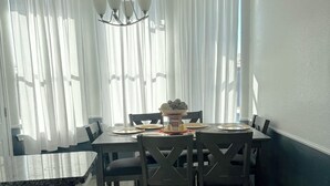 Un coin repas avec une table ronde, six chaises et un lustre.