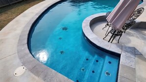 Une piscine à bord incurvé et dotée d’une terrasse carrelée.