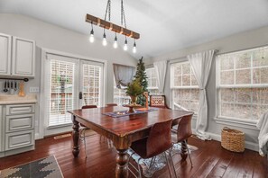 Un coin repas avec une table en bois, des chaises, un lustre et un sapin de Noël.