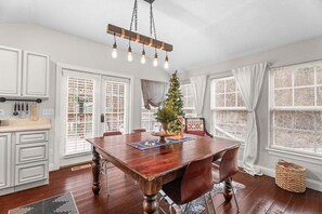 A dining area with a wooden table, chairs, a hanging light fixture, and a Christmas tree. - Creekside Cabin W/ Pool Access & Hot Tub Near Thunder Ridge • Sleeps 4 (Blue Eye)