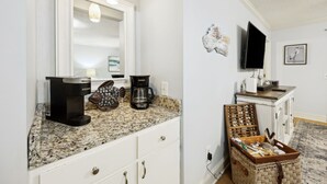 Uma cozinha com bancada de granito, cafeteira e uma cesta de objetos decorativos.