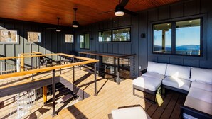 Ein modernes Interieur mit Holzboden, einer Treppe, einer Sitzecke mit Sofa und großen Fenstern mit Blick.