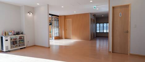 A spacious hallway with wooden flooring, a vending machine, and a door with a sign.