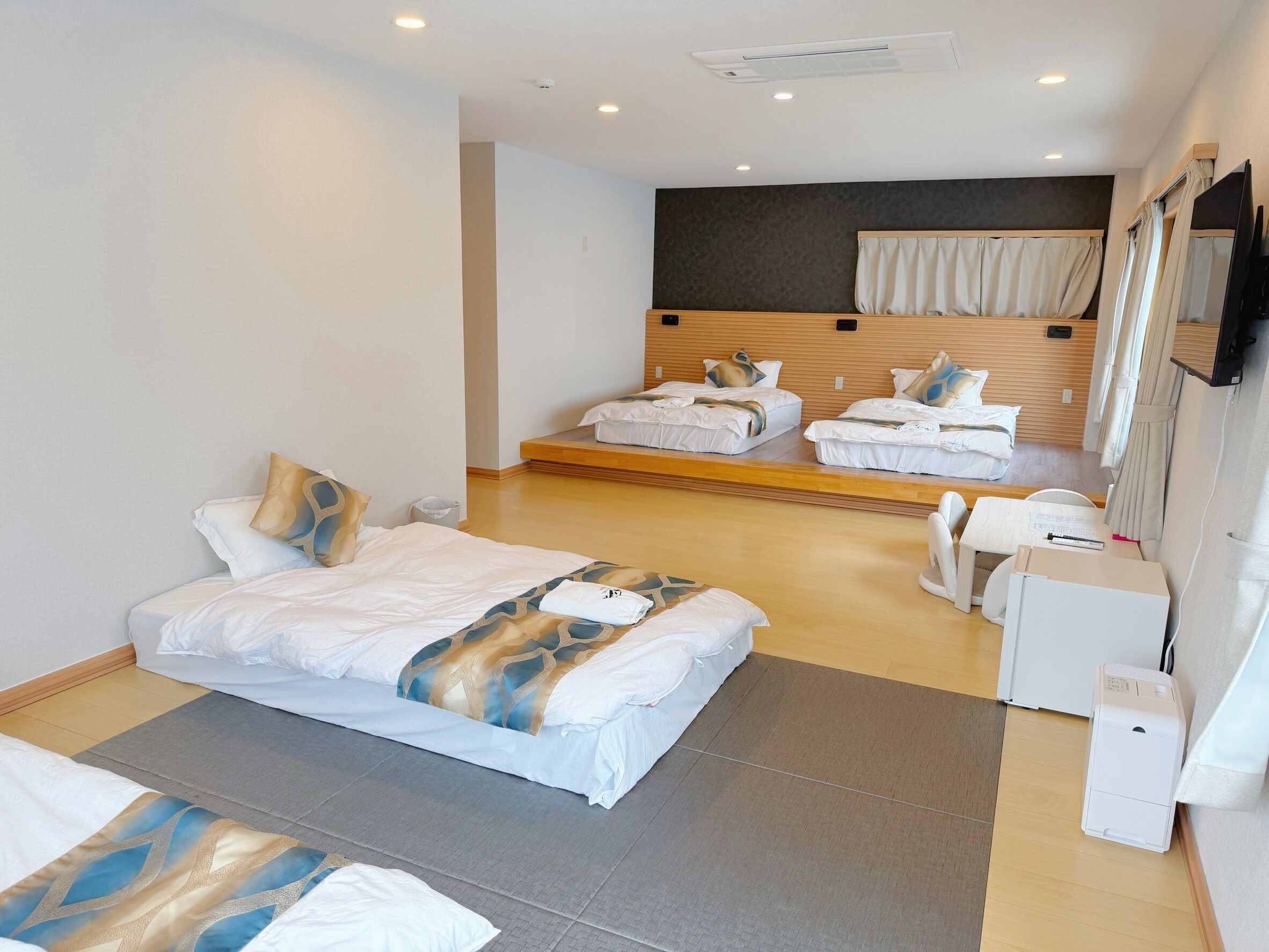 A hotel room with a large bed, a smaller bed, a desk, and a mirror.