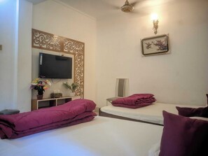 A hotel room with two beds, a TV, a decorative wall panel, a potted plant, and a framed picture.