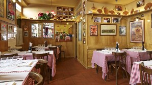 A restaurant with multiple tables covered in red and white checkered tablecloths, wooden walls, and various framed pictures and posters. - Bourgeois apartment 2 min from Bellecour. (Lyon)