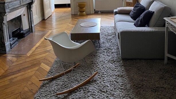 A living room with a fireplace, a sofa, a rocking chair, and a large window. - Bourgeois apartment 2 min from Bellecour. (Lyon)
