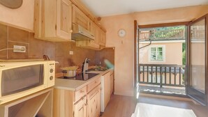 A compact kitchen with wooden cabinets, a microwave, and a sink. - Rochebrune 5th - Flat with Balcony for 4, Claviere, Italy (Claviere)