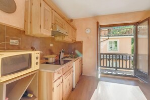 A compact kitchen with wooden cabinets, a microwave, and a sink. - Rochebrune 5th, Claviere, Italy (Claviere)