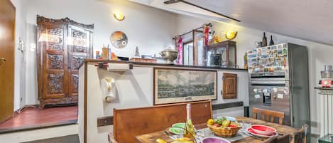 Un comedor con una mesa de madera dispuesta para una comida, un refrigerador con imanes y vistas de la ciudad a través de una ventana.