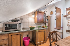 A compact kitchen with wooden cabinets, a microwave, and a sink. - Champlas Suite - Balcony Views, Sleeps 4, Sestriere, Italy (Sestriere)