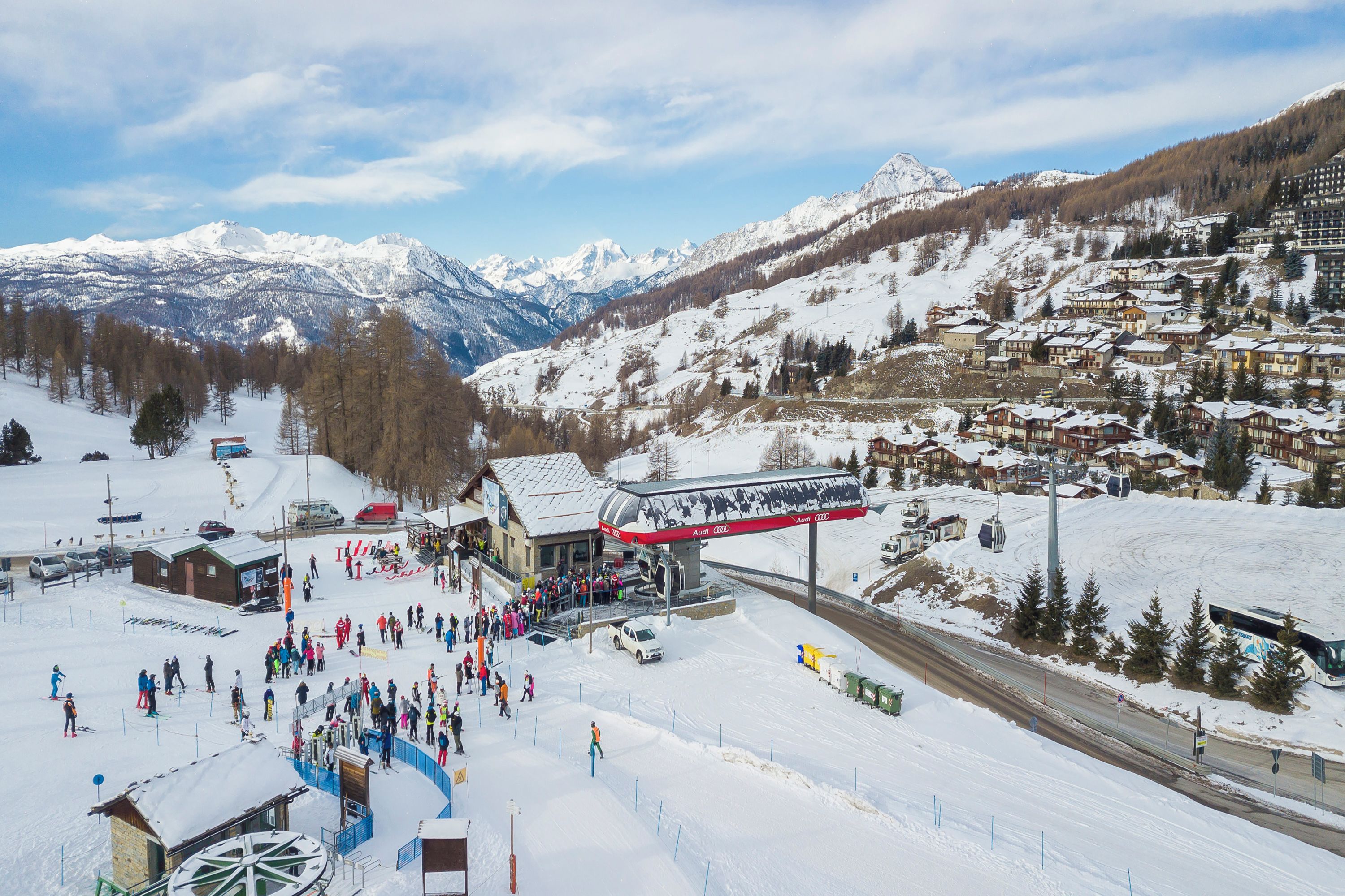 A ski resort with a chairlift, snow-covered mountains, and a town in the background.