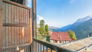 A wooden balcony with a view of a mountain landscape, a red-roofed building, and a stone roof. - Champlas Suite - Balcony Views, Sleeps 4, Sestriere, Italy (Sestriere)