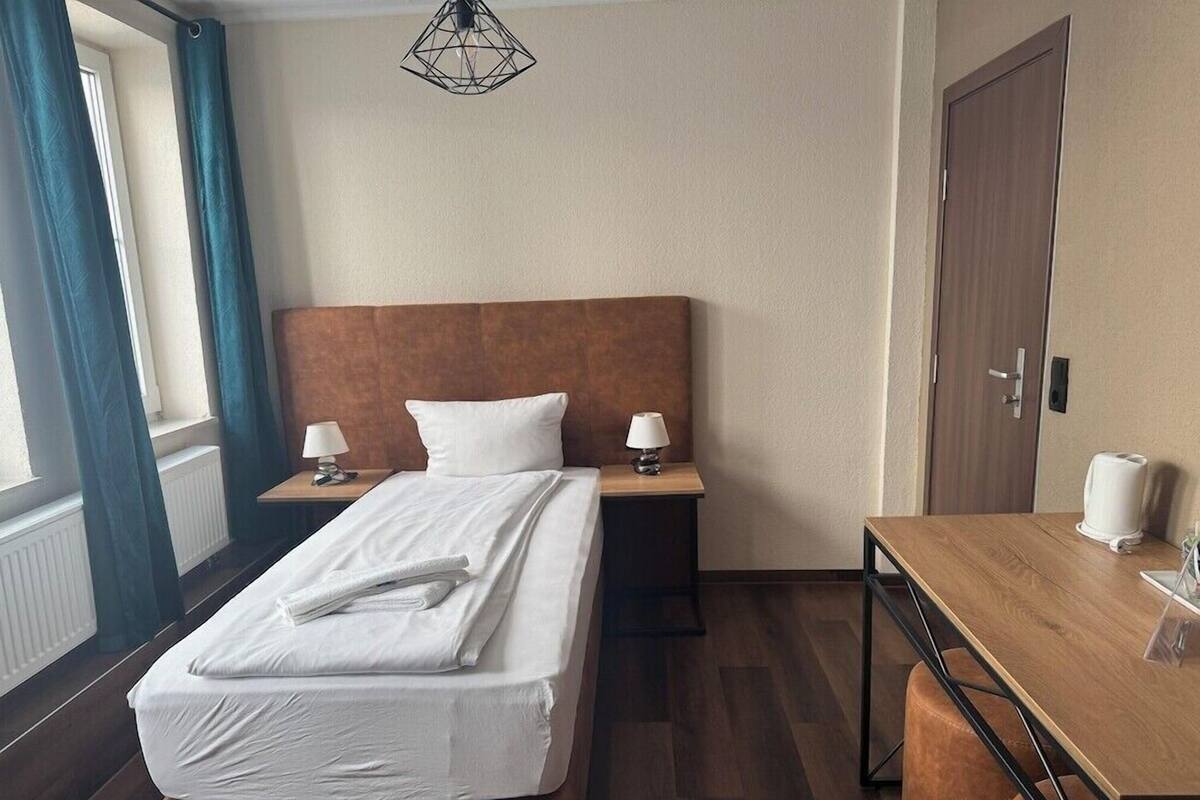 Ein Hotelzimmer mit einem Bett, Nachttischen, einem Schreibtisch und einem Sessel.