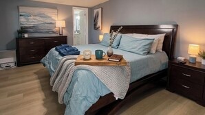 Ein Schlafzimmer mit Bett, Nachttischen, Deckenventilator, Schminktisch und einem Bild an der Wand.