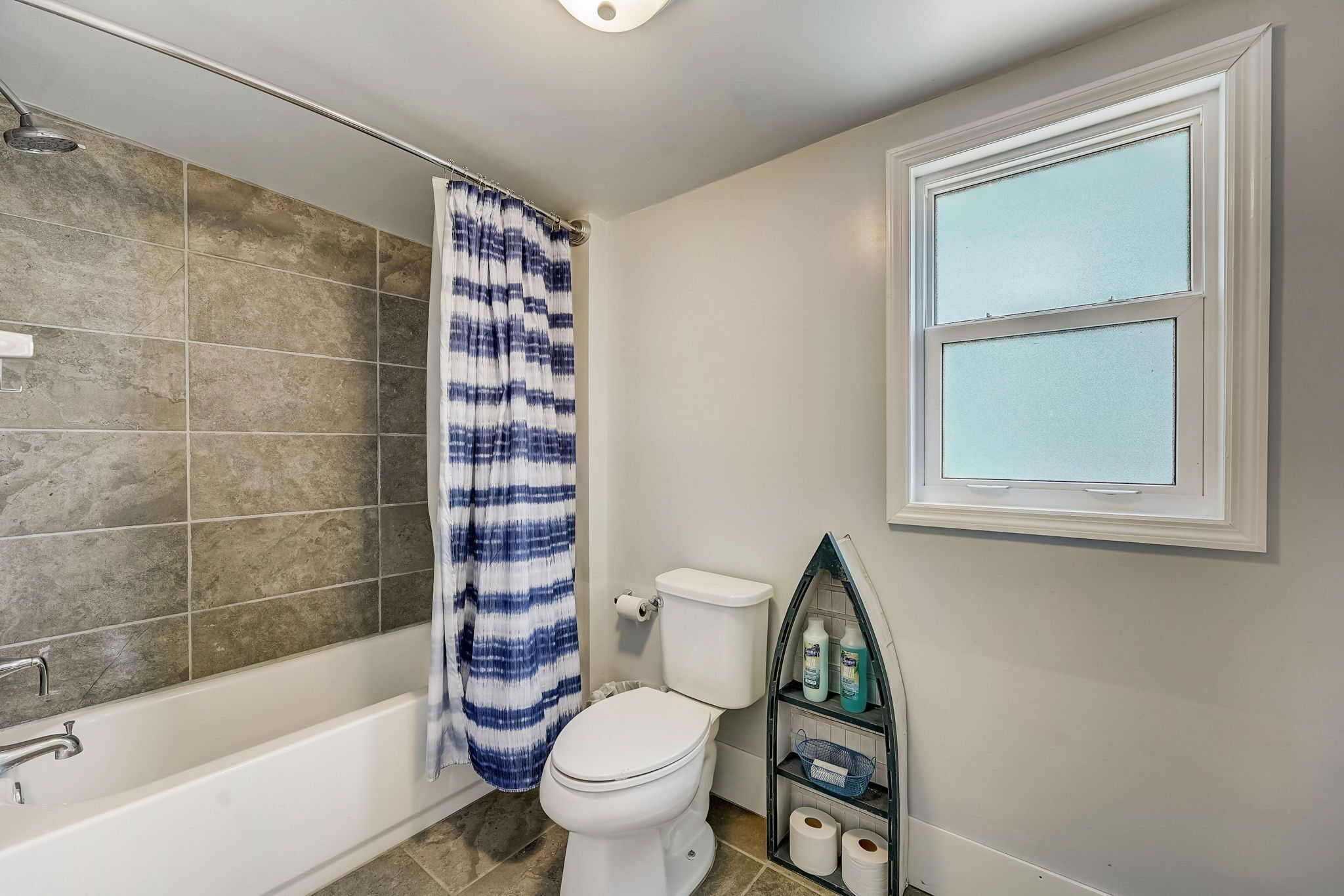 Un baño con bañera, inodoro y ventana.