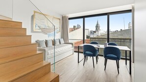 Un apartamento moderno con una escalera, un conjunto de sofás, un comedor y grandes ventanales con vistas a la ciudad.