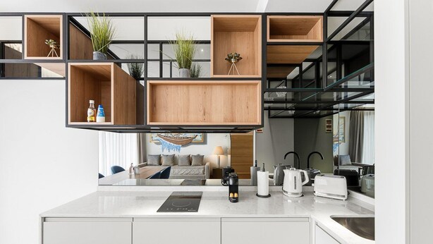 Una cocina moderna con estanterías empotradas de madera, una isla central con cocina por inducción integrada y vistas al área de estar.
