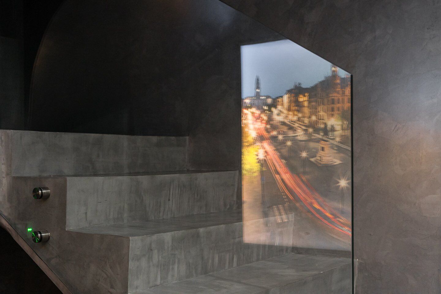 A modern interior with a glass wall reflecting a cityscape at night.
