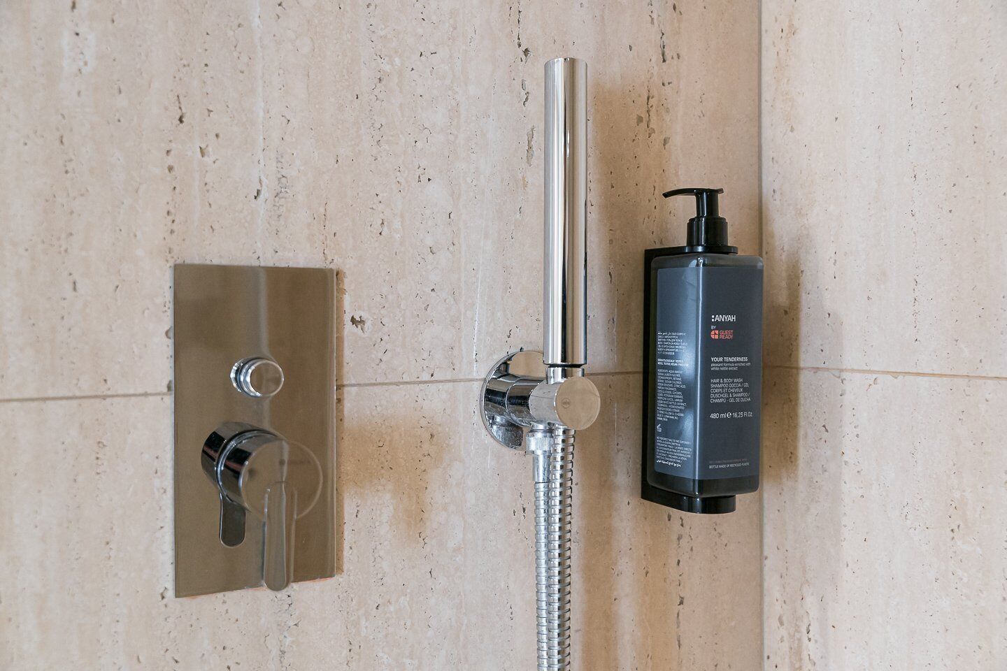 Une douche avec un pommeau de douche amovible et une bouteille de shampoing.