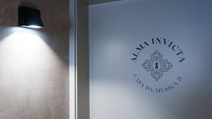 A wall with a light fixture and a framed logo reading "ALMA INVICTA CASA DA MÚSICA". - GuestReady - Alma Invicta 'Casa da Música II' (Porto)