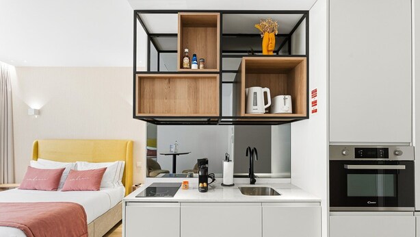 A compact hotel room with a bed, a small kitchenette, and a built-in oven. - GuestReady - Alma Invicta 'Casa da Música II' (Porto)