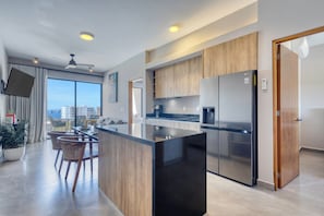 A modern kitchen with a large island, stainless steel appliances, and wooden cabinetry. - 2-bedroom apartment in pleasant Cabo San Lucas with AC (Cabo San Lucas)