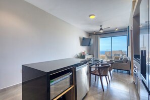 A modern kitchen with a black countertop, stainless steel appliances, and a large window offering a city view. - 2-bedroom apartment in pleasant Cabo San Lucas with AC (Cabo San Lucas)
