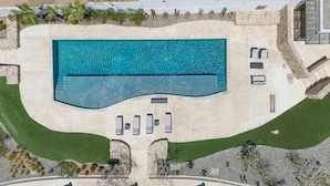 An aerial view of a rectangular swimming pool with a stone deck, surrounded by a landscaped area with grass and plants. - 2-bedroom apartment in pleasant Cabo San Lucas with AC (Cabo San Lucas)