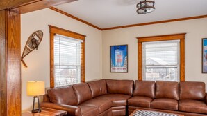 A living room with a brown leather sectional sofa, a wooden coffee table, and a chessboard. - The Osborne House 1930 near Gore Mountain with ARCADE! Air conditioned! (North Creek)