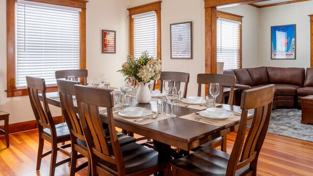 A dining area with a wooden table set for six, surrounded by wooden chairs. - The Osborne House 1930 near Gore Mountain with ARCADE! Air conditioned! (North Creek)
