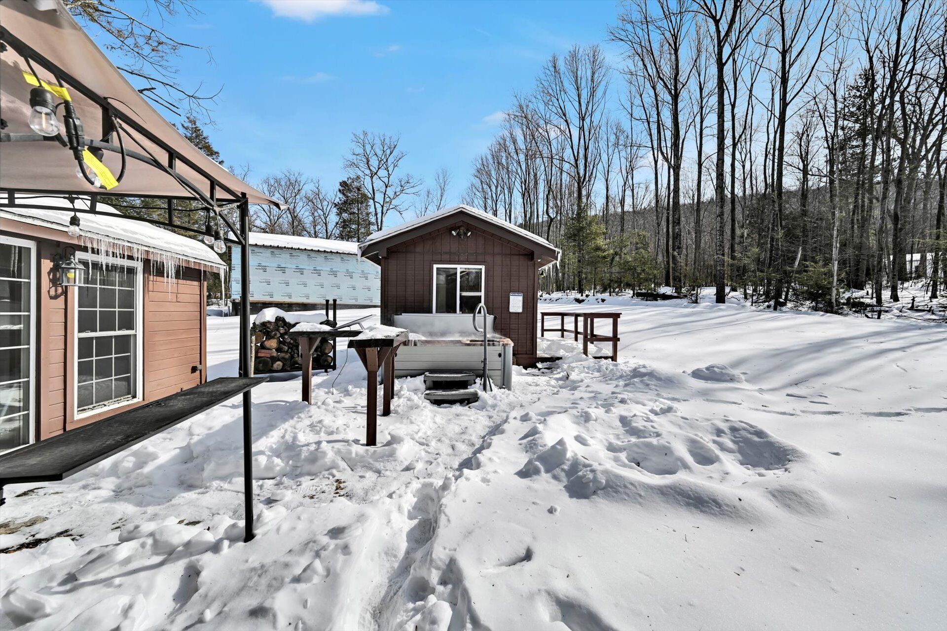 A cabin with a snow-covered deck, a small porch, and a wooden exterior.