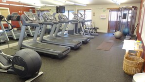 Ett gym med löpband, träningsbollar och en styrketräningsmaskin.