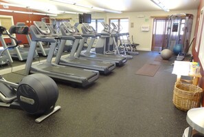 Ein Fitnessstudio mit Laufbändern, Gymbällen und einem Kraftgerät.