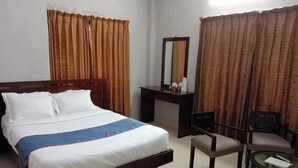 Ein Hotelzimmer mit einem Bett, einem Schreibtisch, einem Stuhl und einem kleinen Tisch.