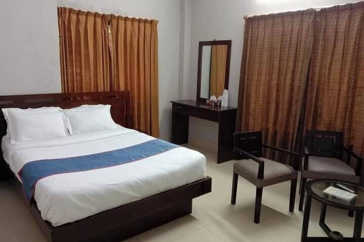 Una habitación de hotel con cama, escritorio, silla y una mesita.