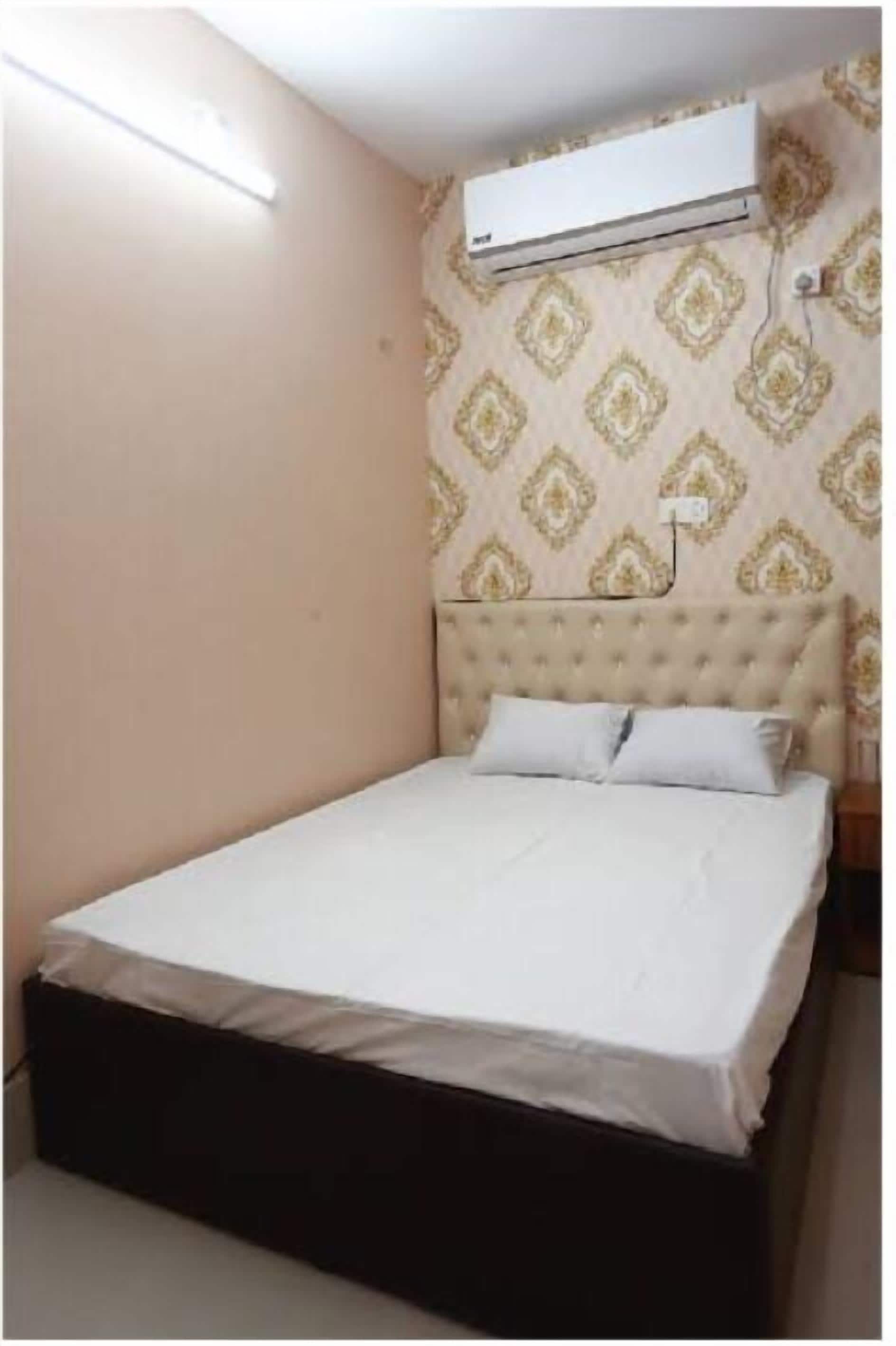 Une chambre à coucher avec un lit, un climatiseur fixé au mur et un papier peint à motifs.