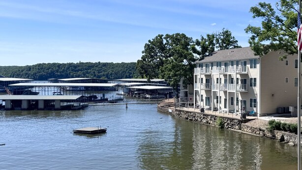 A waterfront property with a dock, a building with balconies, and a flagpole.