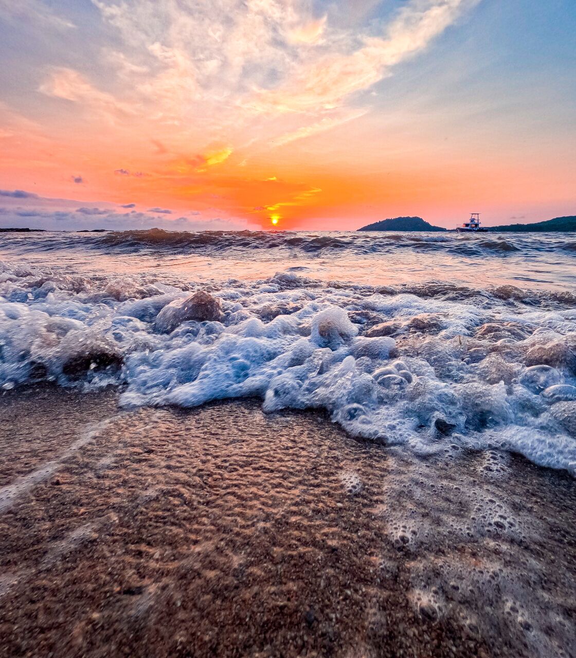 Ein Strand bei Sonnenuntergang, mit Wellen.