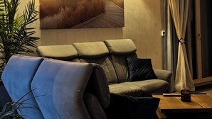 A modern living room with a sofa, a painting of a lighthouse, and two wall-mounted lights.