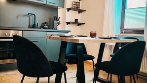 Een moderne keuken met een houten tafel, zwarte stoelen en hangende lampen.