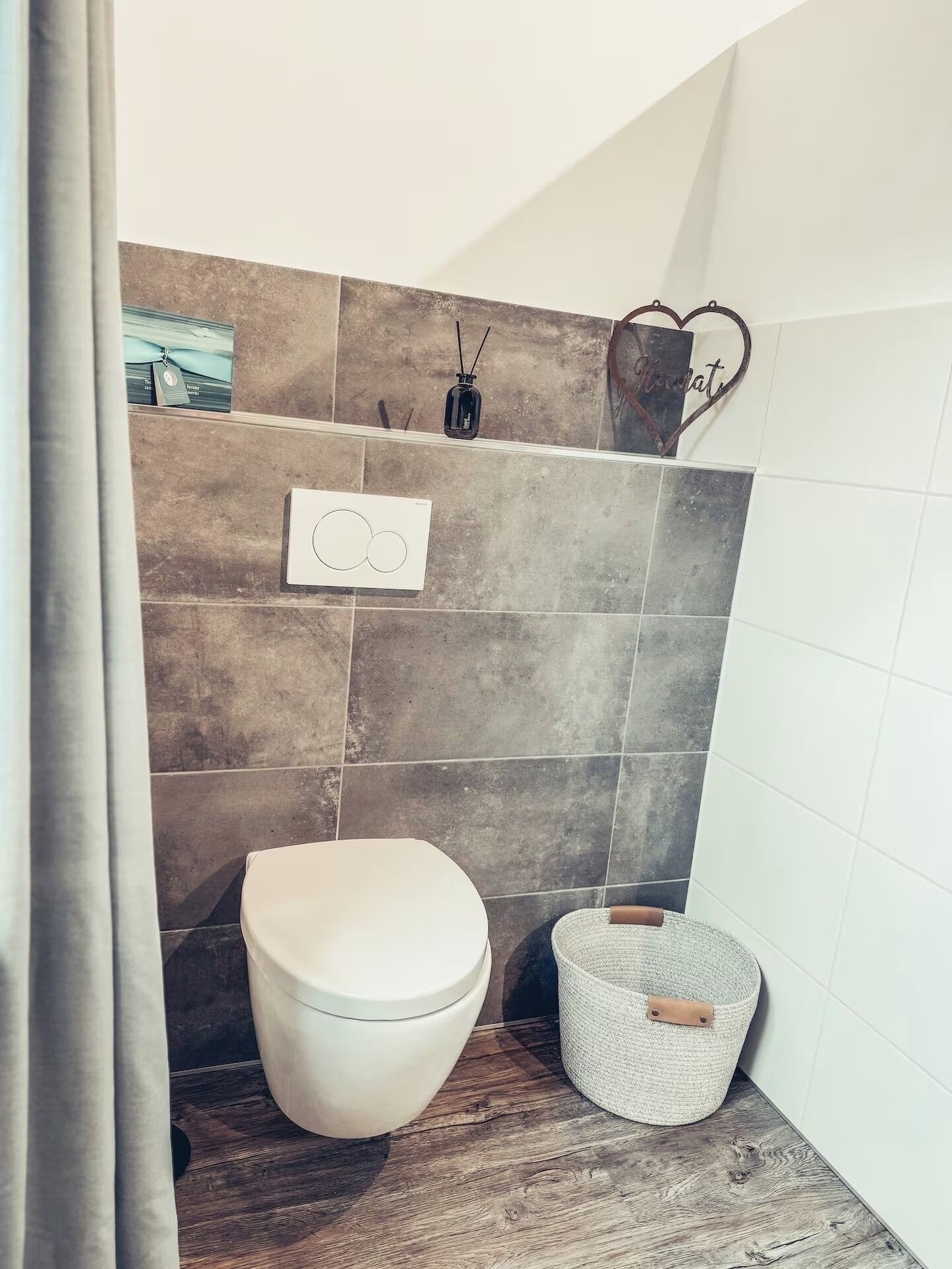 A bathroom with a white toilet, a woven basket, and a wall-mounted soap dispenser.