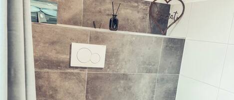A bathroom with a white toilet, a woven basket, and a wall-mounted soap dispenser.