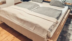 Een slaapkamer met een groot bed, een kledingkast, een nachtkastje en een wandplank.