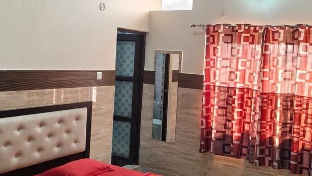 A bedroom with a bed, a ceiling fan, a window, and a door. - Sudama Krishna Residency (Mathura)