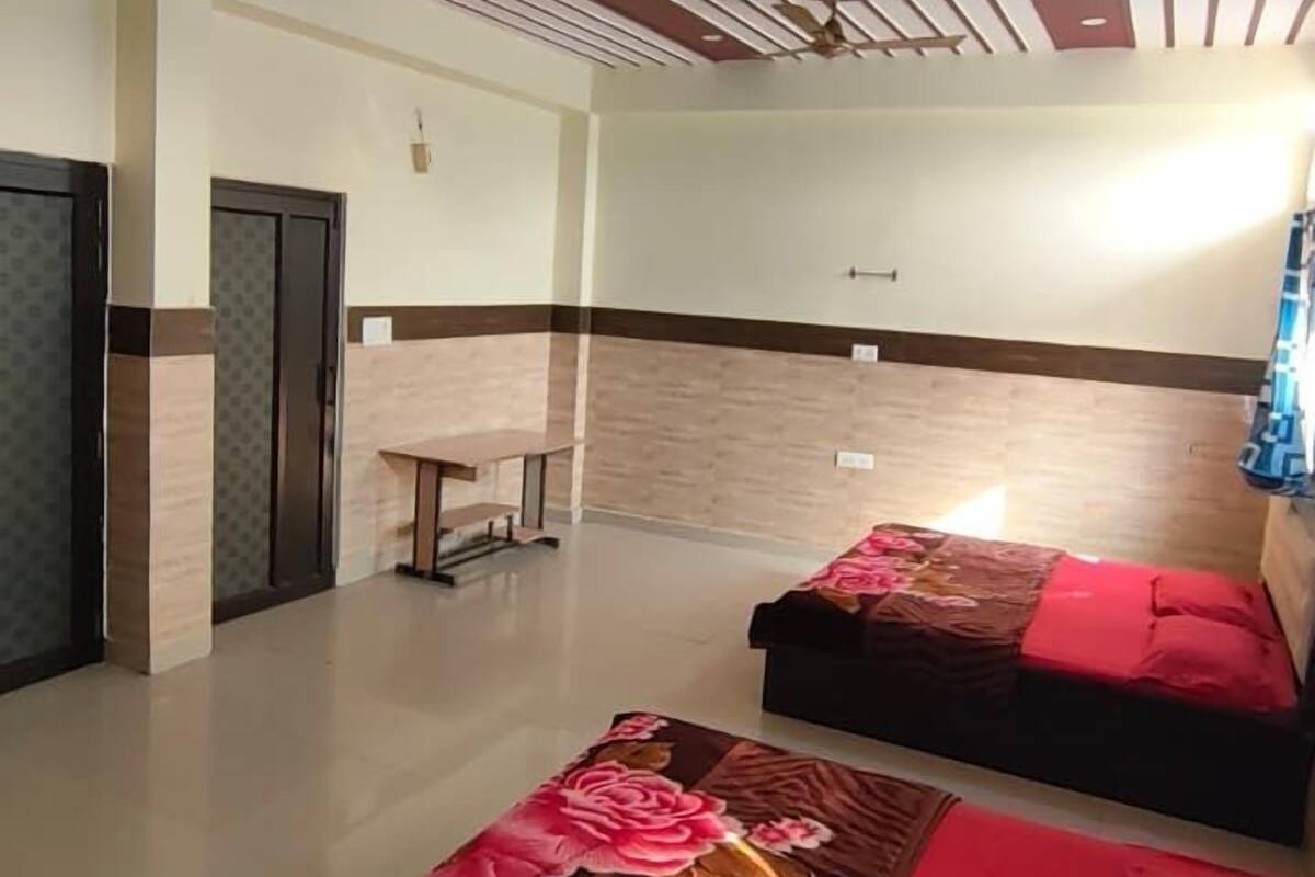 A hotel room with two beds, a ceiling fan, a small table, and a wall-mounted light.