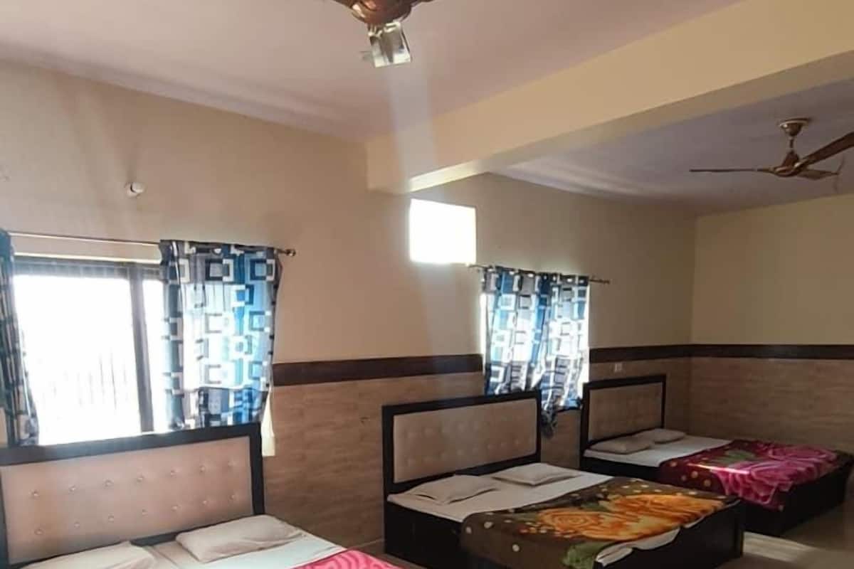 A hotel room with three beds, a ceiling fan, and a window with curtains.