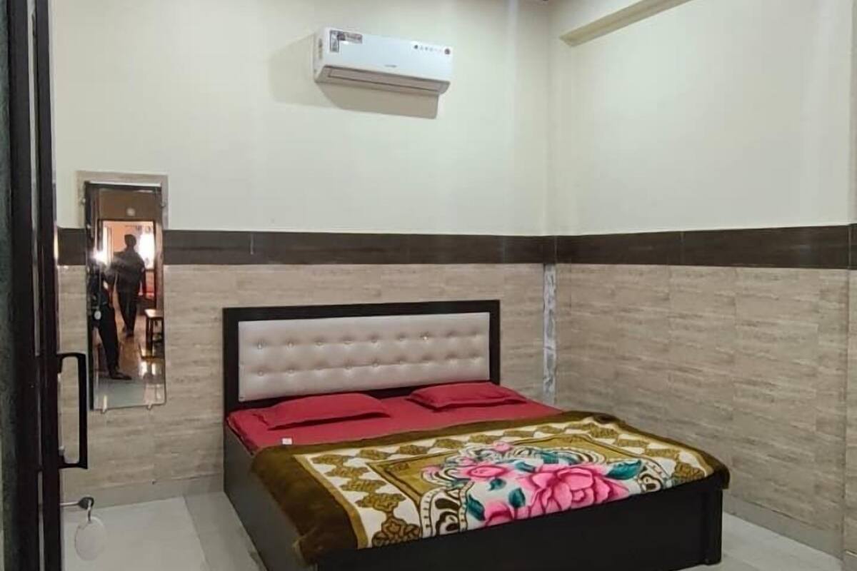 A bedroom with a bed, a ceiling fan, an air conditioning unit, and a mirror.